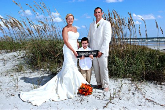 bride and groom and child on beach