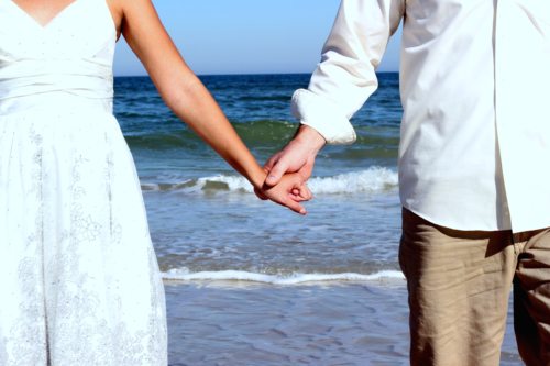 bride and groom holding hands at the beach