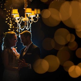 bride and groom under chandelier