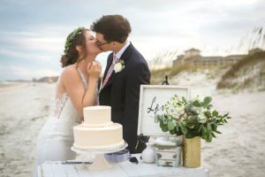 bride and groom kissing near cake table at beachfront wedding, beach wedding, winter beach wedding