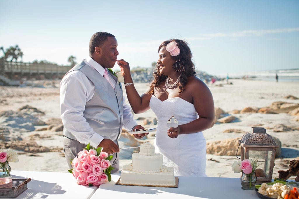 bride feeding groom cake at beach wedding