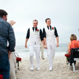 two gay men walking down the aisle in white suits and black shirts, gay marriage, same sex wedding