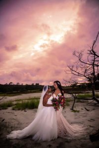 two lesbian women in white wedding dresses posing together on the beach under a stormy sky, gay marriage, same sex wedding