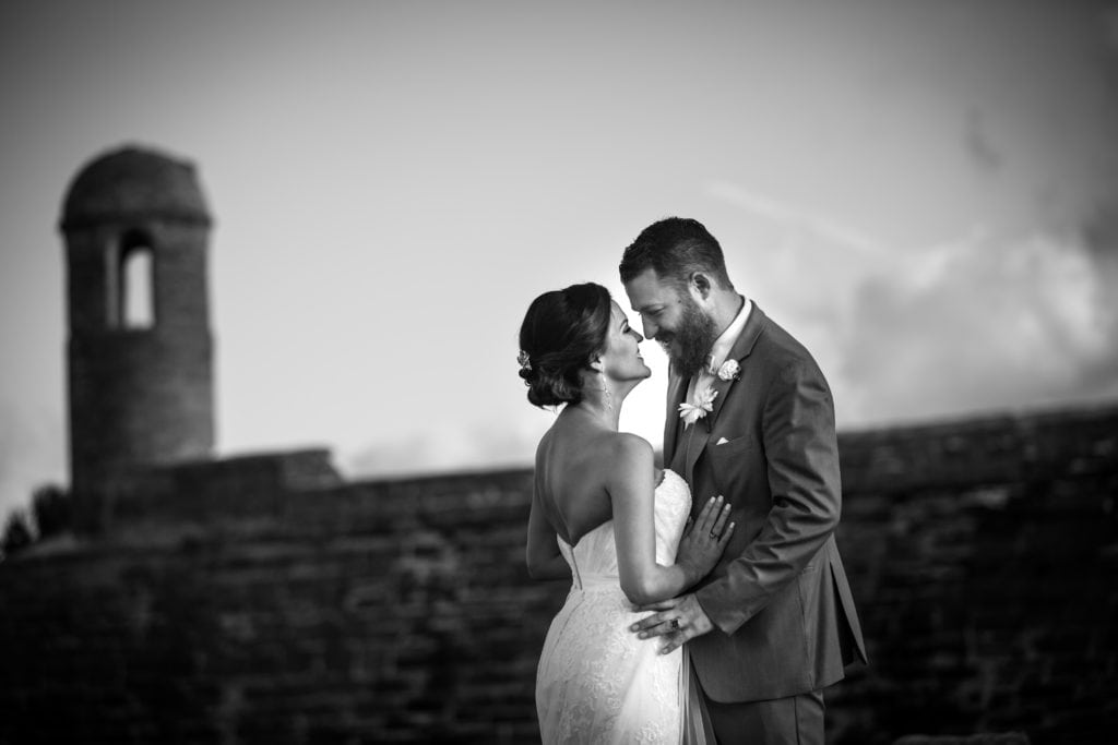 bride and groom embracing in front of historic fort