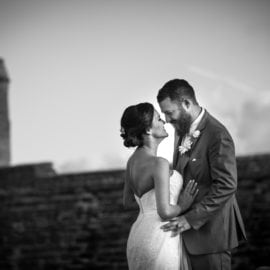 bride and groom embracing in front of historic fort