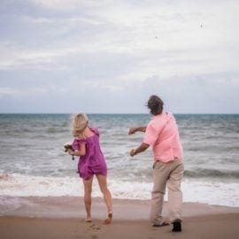 bride and groom throwing shells into ocean