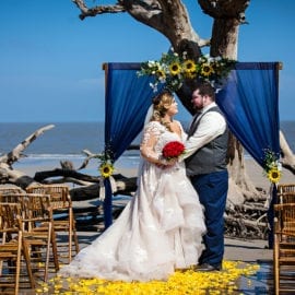 bride and groom in front of beach wedding arbor