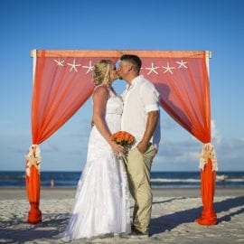 bride and groom in front of beach wedding arbor