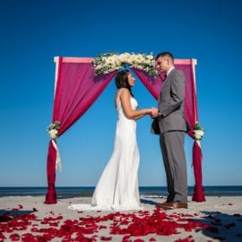 bride and groom in front of beach wedding arbor