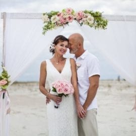 bride and groom in front of beach wedding arbor