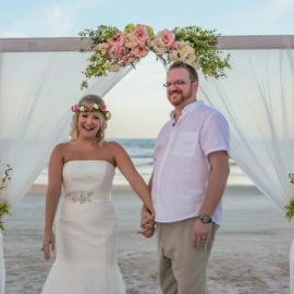 bride and groom in front of beach wedding arbor