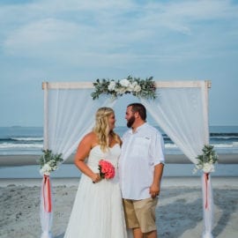 bride and groom in front of beach wedding arbor