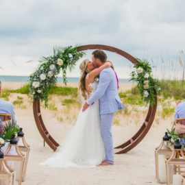 a bride and groom at the altar kissing in front of a boho arch, florida beach wedding, wedding planner