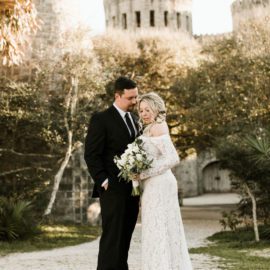 Bride and groom posed stylishly in front of castle