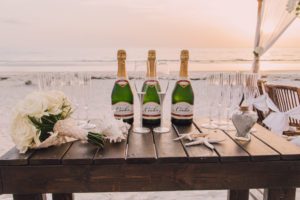 a table with champagne set out on the beach for a beach wedding ceremony, beach wedding, wedding after party