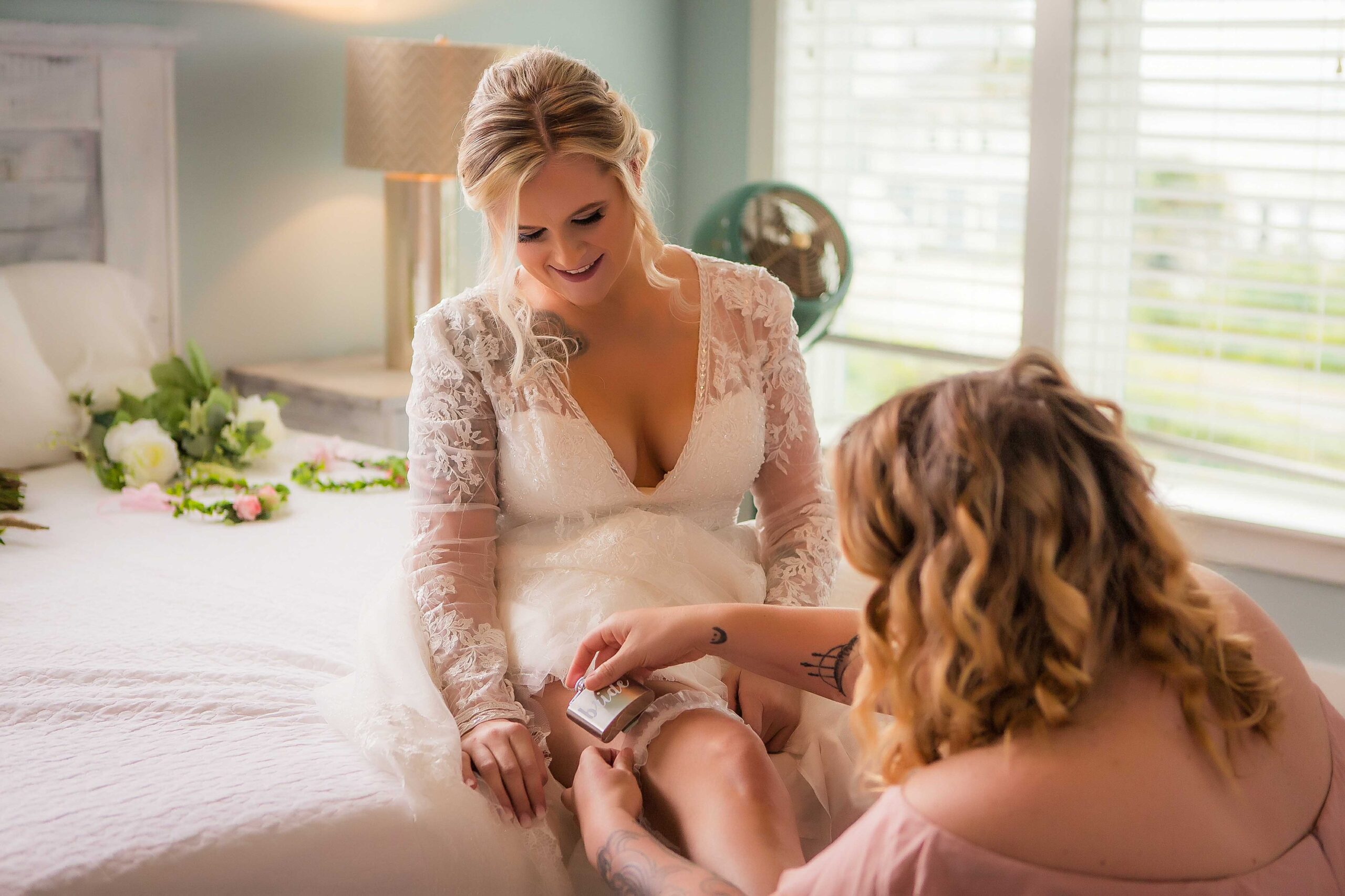 a bridemaid putting the garter on the bride before beach wedding, wedding insurance, flo