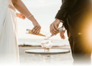 artistic shot of bride and groom pouring sand at beachfront altar, beach wedding, unity ceremony ideas with children