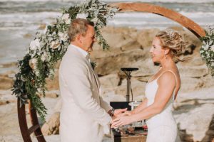 Bride and groom holding hands at beachfront altar, beach wedding, how to include stepchildren in wedding ceremony