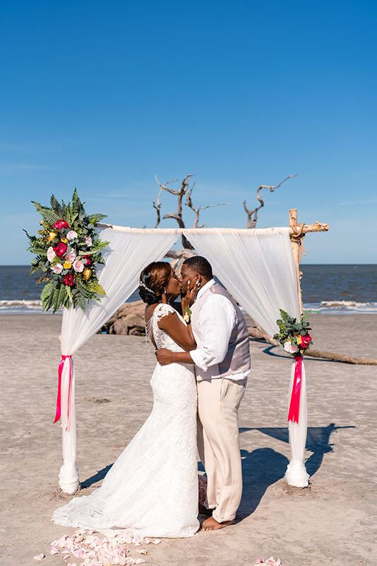 Bride and groom kissing on the beach during their wedding with the charmingly vintage all inclusive wedding package, jekyll island, wedding planner