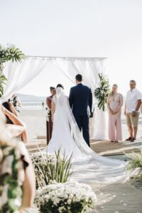 a bride and groom standing at the altar on a beach wedding venue, how to write wedding vows, wedding vows