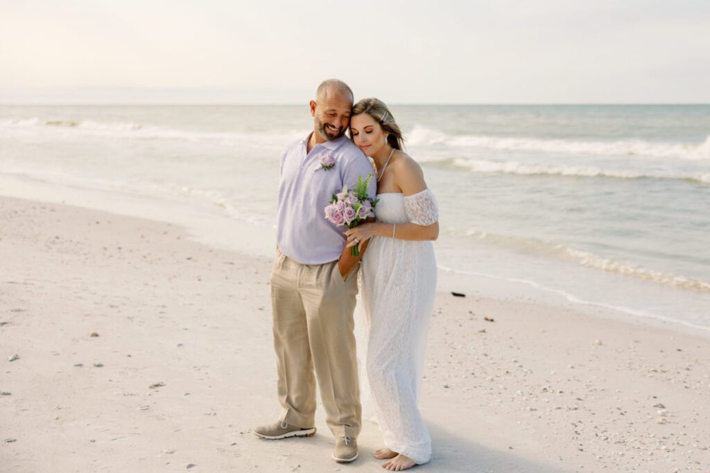 a groom and bride posing together on the beach after their beach wedding, non wedding ceremony